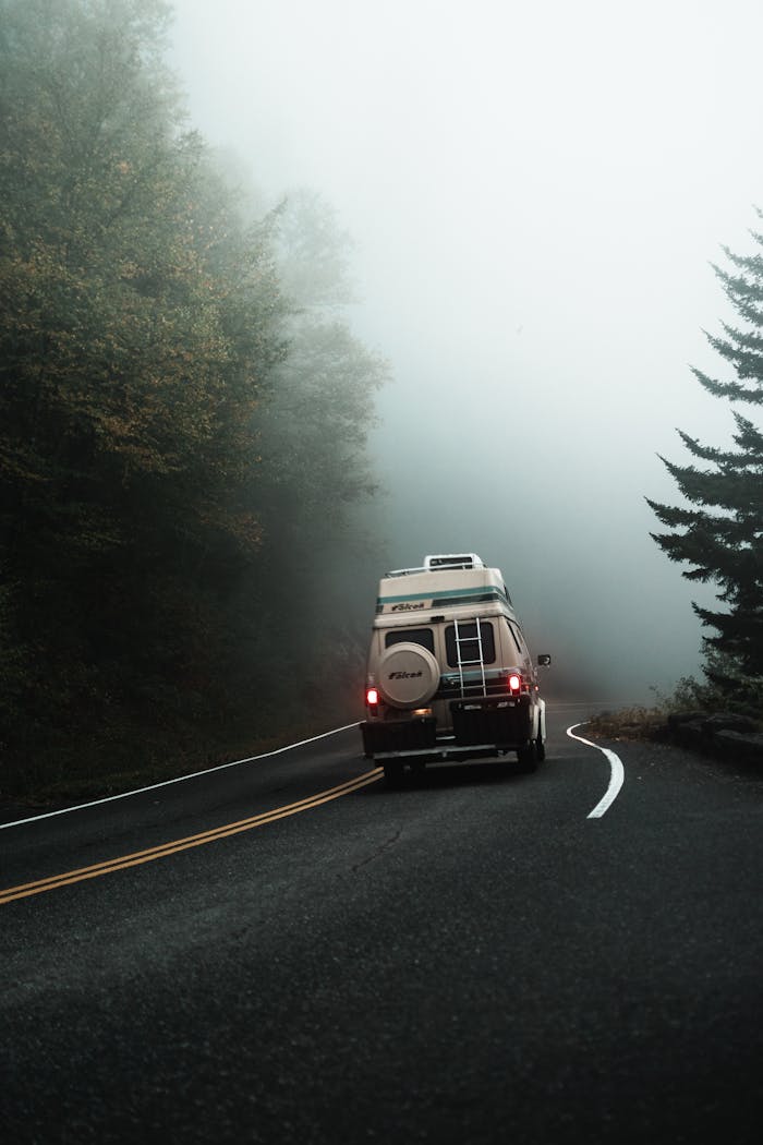 about-03 A camper van travels through a foggy rural road, creating a serene scene for adventure.